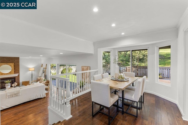 dining space with dark wood-type flooring, a fireplace, and crown molding