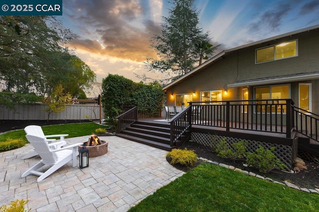 exterior space with a wooden deck, a yard, a patio area, and an outdoor fire pit