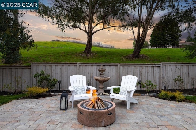 patio terrace at dusk featuring a lawn and an outdoor fire pit