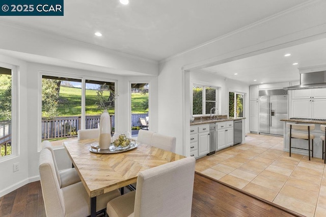 dining room featuring sink, crown molding, and light hardwood / wood-style flooring