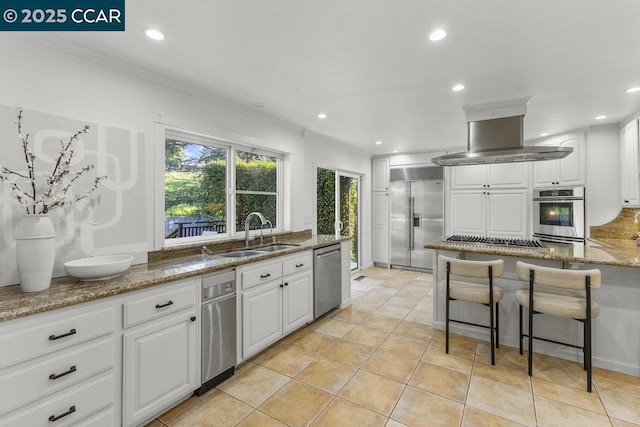 kitchen featuring sink, island exhaust hood, white cabinets, and appliances with stainless steel finishes