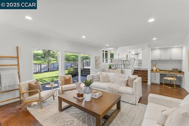 living room with crown molding, built in desk, and light hardwood / wood-style flooring