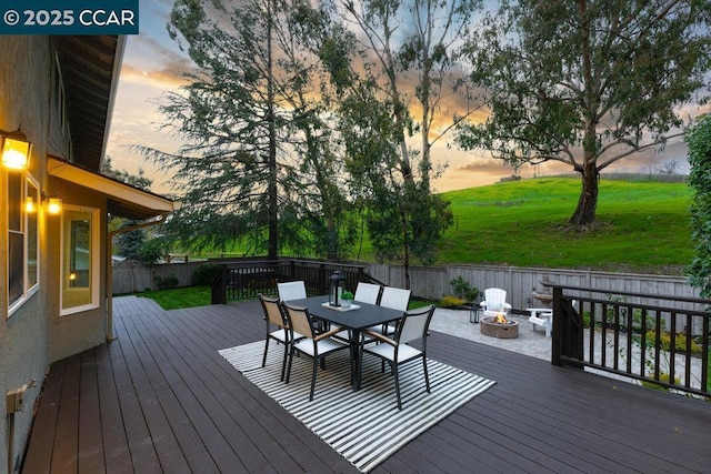 deck at dusk with an outdoor fire pit and a yard