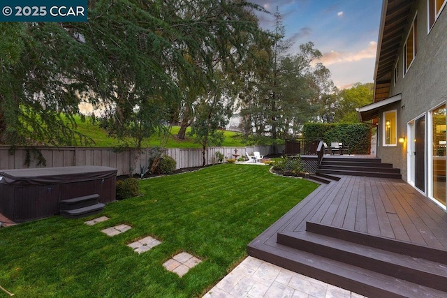 yard at dusk with a hot tub and a deck