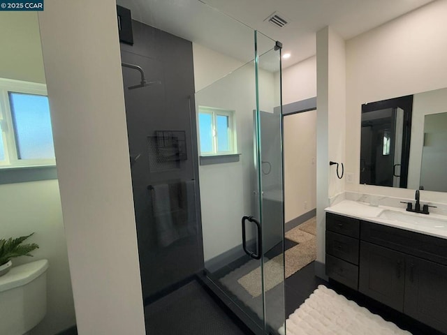 bathroom with walk in shower, vanity, and toilet