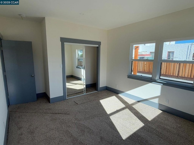 unfurnished bedroom featuring a closet and dark colored carpet