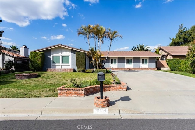 view of front of house with a front yard, driveway, and an outdoor fire pit