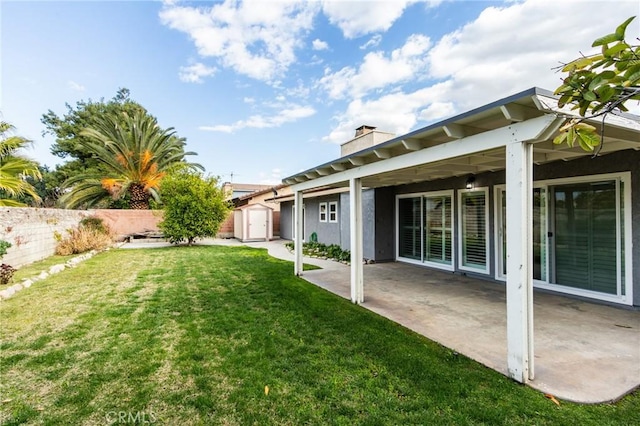 view of yard with a shed, fence, a patio, and an outdoor structure