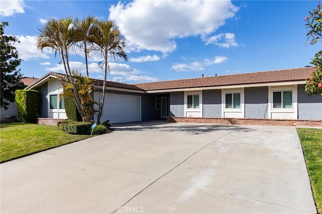 ranch-style house featuring a garage, concrete driveway, a front yard, and stucco siding