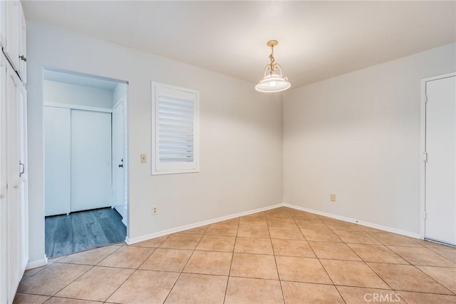 unfurnished room with light tile patterned floors and baseboards