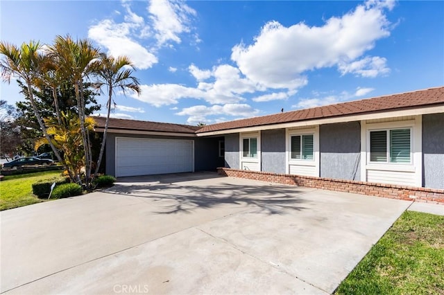 ranch-style house featuring a garage, concrete driveway, and stucco siding