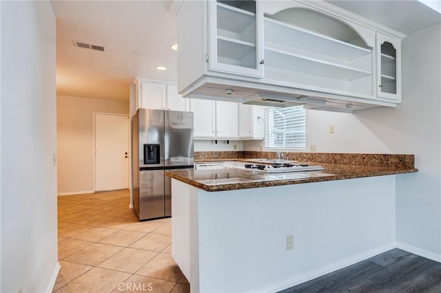 kitchen featuring a peninsula, visible vents, white cabinets, stainless steel refrigerator with ice dispenser, and dark stone counters