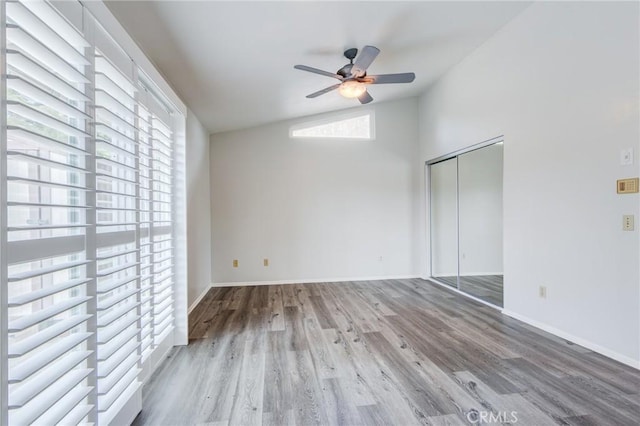 spare room with ceiling fan, baseboards, vaulted ceiling, and wood finished floors