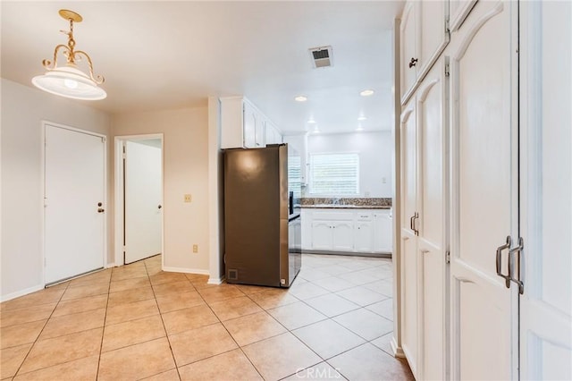 kitchen with white cabinetry, freestanding refrigerator, visible vents, and light tile patterned floors