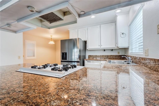 kitchen featuring a peninsula, white appliances, a sink, white cabinets, and dark stone countertops