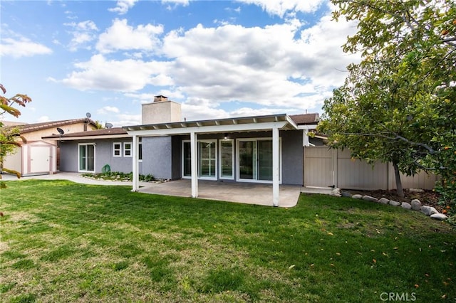 back of house featuring a patio, a chimney, a lawn, fence, and a shed