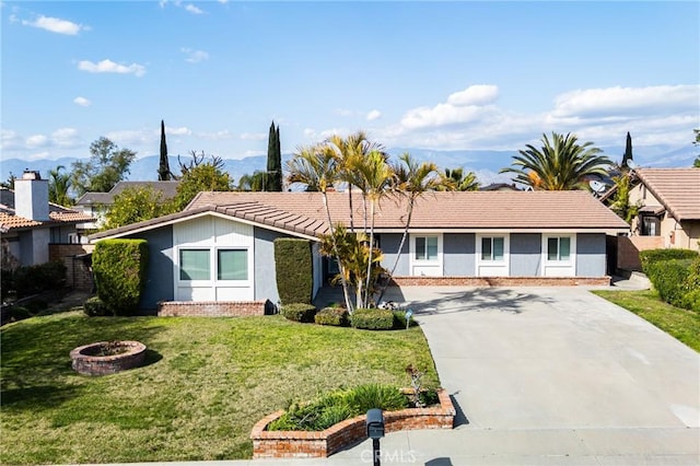 single story home featuring a tiled roof, a front lawn, and brick siding