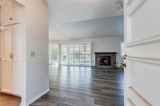 unfurnished living room with a fireplace, baseboards, vaulted ceiling, and dark wood-style flooring