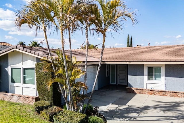 ranch-style home with concrete driveway, an attached garage, and stucco siding