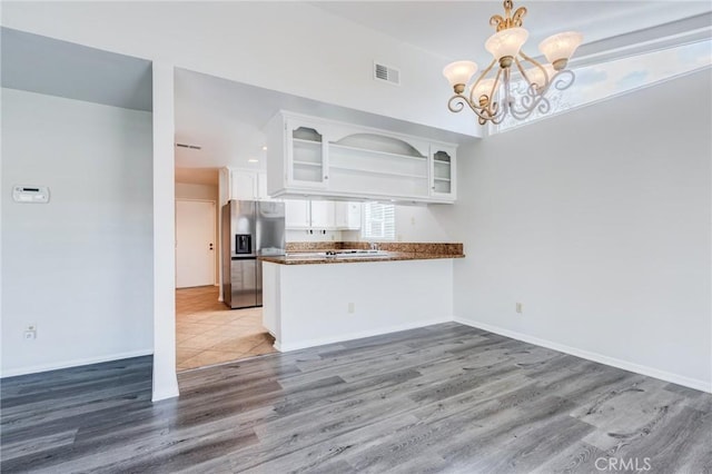 kitchen with dark countertops, visible vents, an inviting chandelier, white cabinets, and stainless steel fridge with ice dispenser