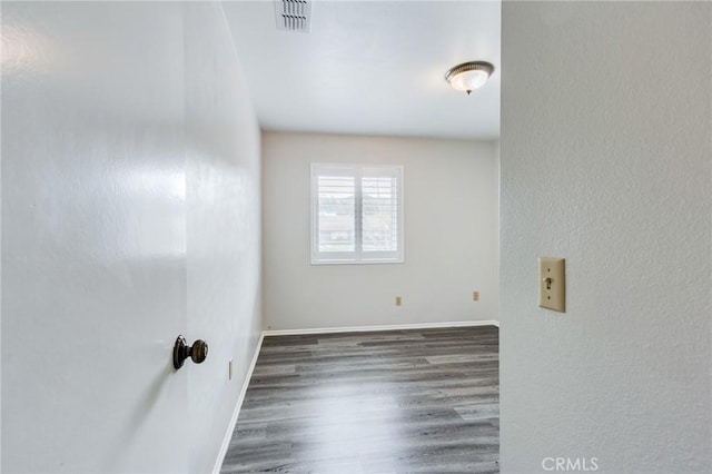 unfurnished room with visible vents, baseboards, and wood finished floors