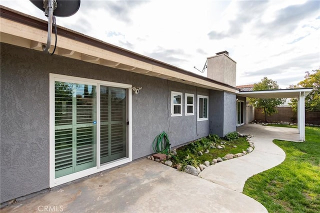 exterior space featuring fence, a patio, a chimney, and stucco siding