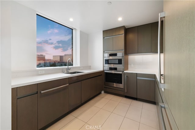 kitchen featuring sink, dark brown cabinets, stainless steel double oven, and light tile patterned floors