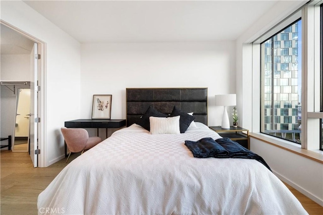 bedroom with a walk in closet, light hardwood / wood-style floors, and a closet