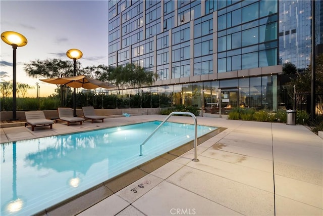 pool at dusk featuring a patio