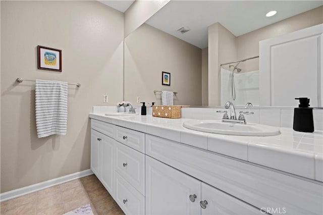 bathroom with walk in shower, vanity, and tile patterned flooring