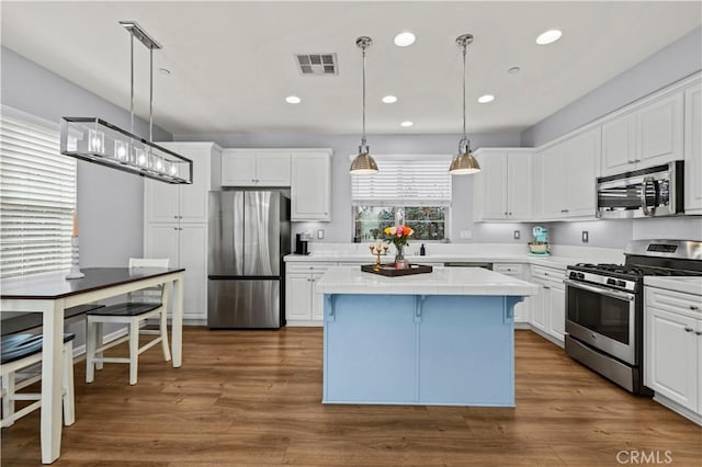 kitchen featuring stainless steel appliances, a center island, pendant lighting, and white cabinets