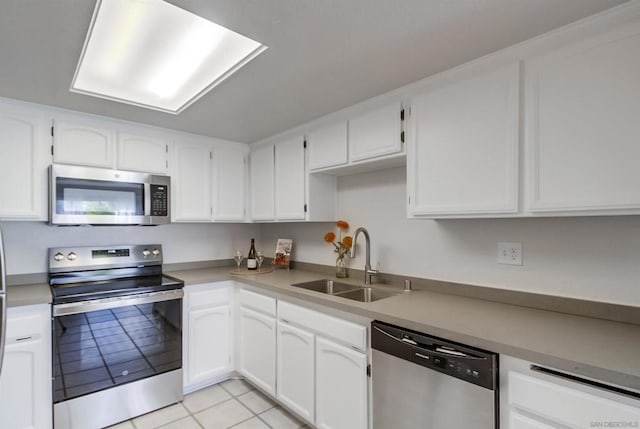 kitchen with sink, white cabinets, light tile patterned floors, and stainless steel appliances