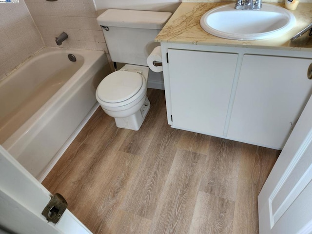 bathroom featuring hardwood / wood-style floors, toilet, vanity, and a bathing tub