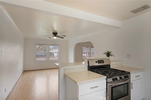 kitchen with white cabinetry, light wood-type flooring, kitchen peninsula, ceiling fan, and stainless steel range with gas cooktop