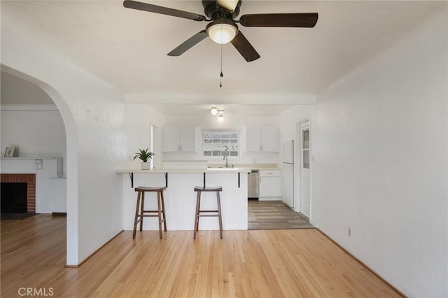 kitchen with white cabinetry, white fridge, kitchen peninsula, stainless steel dishwasher, and a breakfast bar area