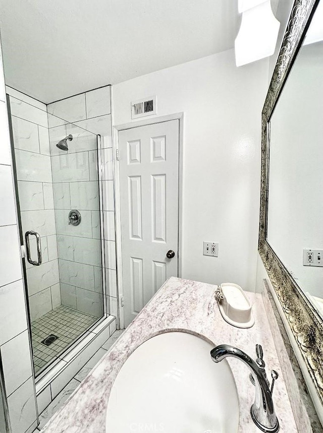 bathroom featuring a shower with door and vanity