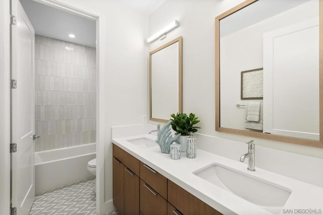 full bathroom featuring tiled shower / bath, vanity, and toilet