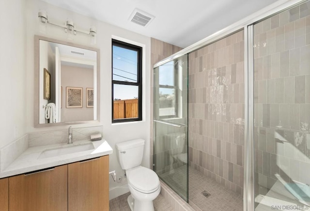 bathroom featuring vanity, a shower with shower door, and toilet