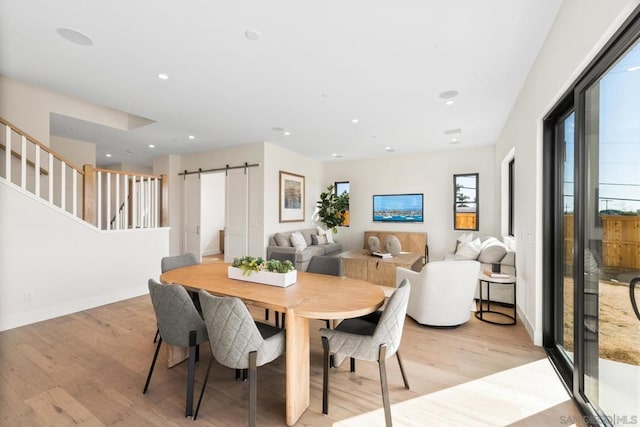 dining area with a barn door and light hardwood / wood-style floors