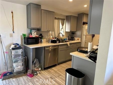 kitchen featuring sink, refrigerator, stainless steel dishwasher, and gray cabinets