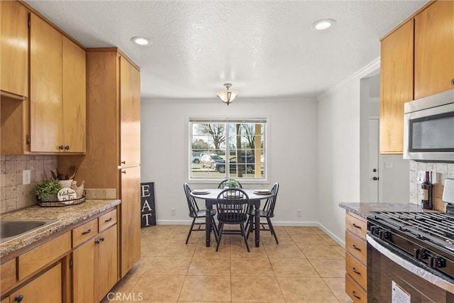 kitchen with tasteful backsplash, light tile patterned floors, light stone countertops, ornamental molding, and gas stove