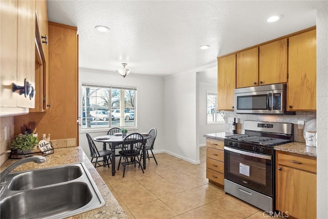 kitchen with stainless steel appliances, sink, backsplash, light tile patterned floors, and crown molding