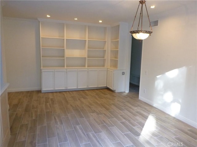 unfurnished room with built in shelves and ornamental molding