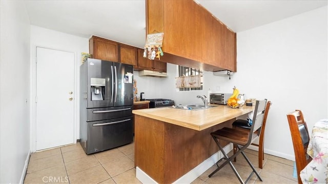 kitchen with a kitchen bar, sink, stainless steel fridge with ice dispenser, kitchen peninsula, and light tile patterned floors