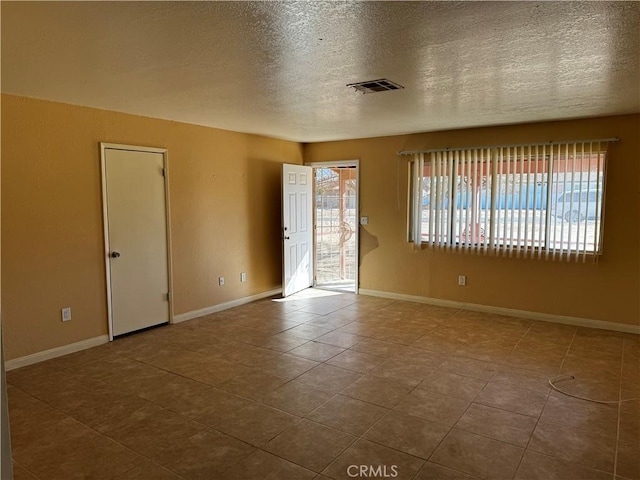 spare room featuring tile patterned floors and a textured ceiling