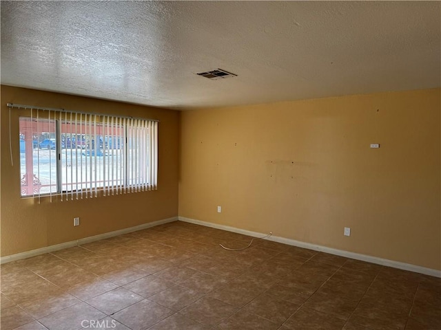 spare room with a textured ceiling and tile patterned floors