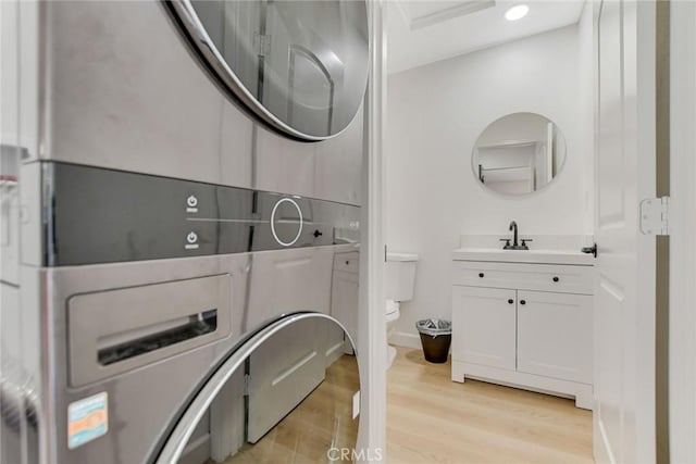 washroom with stacked washer / dryer, sink, and light hardwood / wood-style flooring