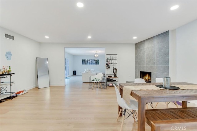 dining area featuring light wood-type flooring and a fireplace