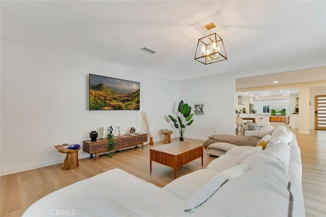 living room with light hardwood / wood-style floors and an inviting chandelier