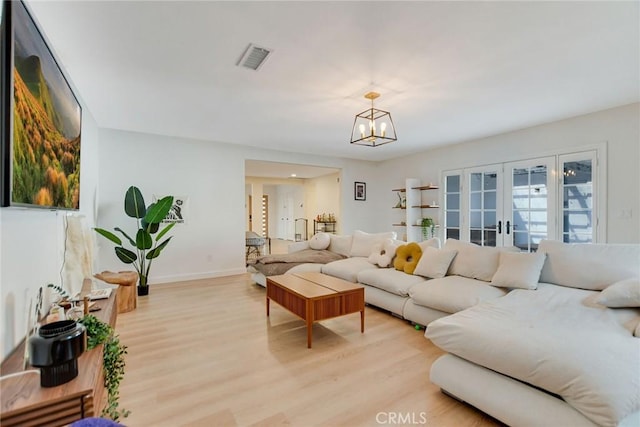 living room featuring a chandelier, light hardwood / wood-style flooring, and french doors